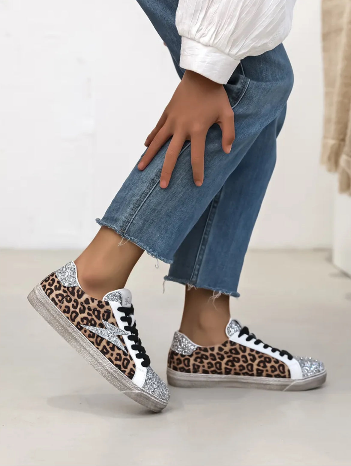 Notre basket Romy en suédine léopard et paillettes argentées est l'accessoire parfait pour un look unique et original. Avec sa découpe en éclair sur les côtés, elle apporte une touche de fantaisie à toutes vos tenues. Confortable et tendance, elle ne pourra que vous séduire !
